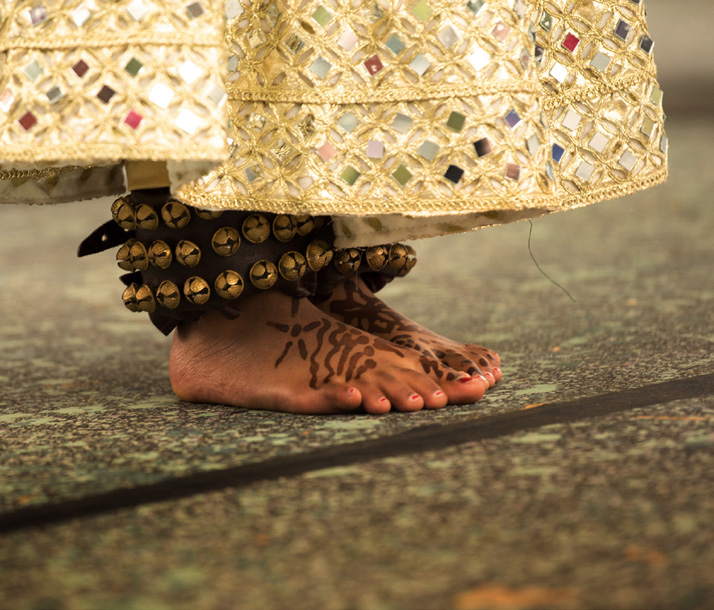 Pés de dançarina com guizos e henna sobre o chão de pedra